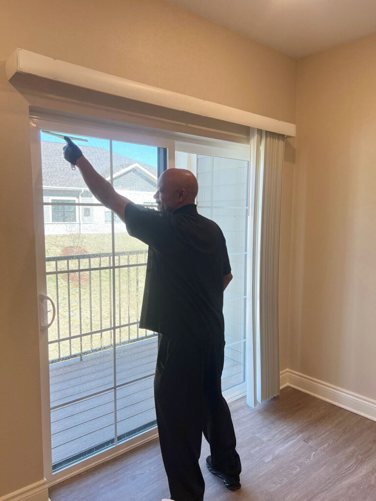 A man wiping down a sliding glass door in a room.