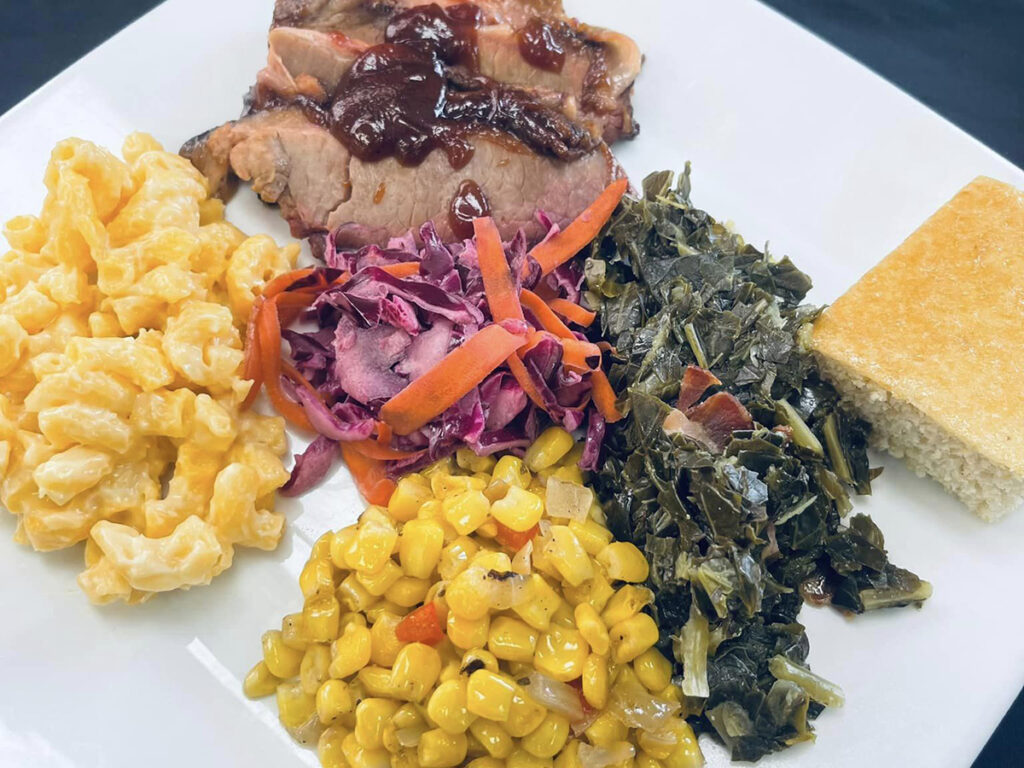 Beef BBQ brisket, cheesy baked macaroni, collard greens with corn, and a tangy red cabbage salad. A delicious feast awaits!