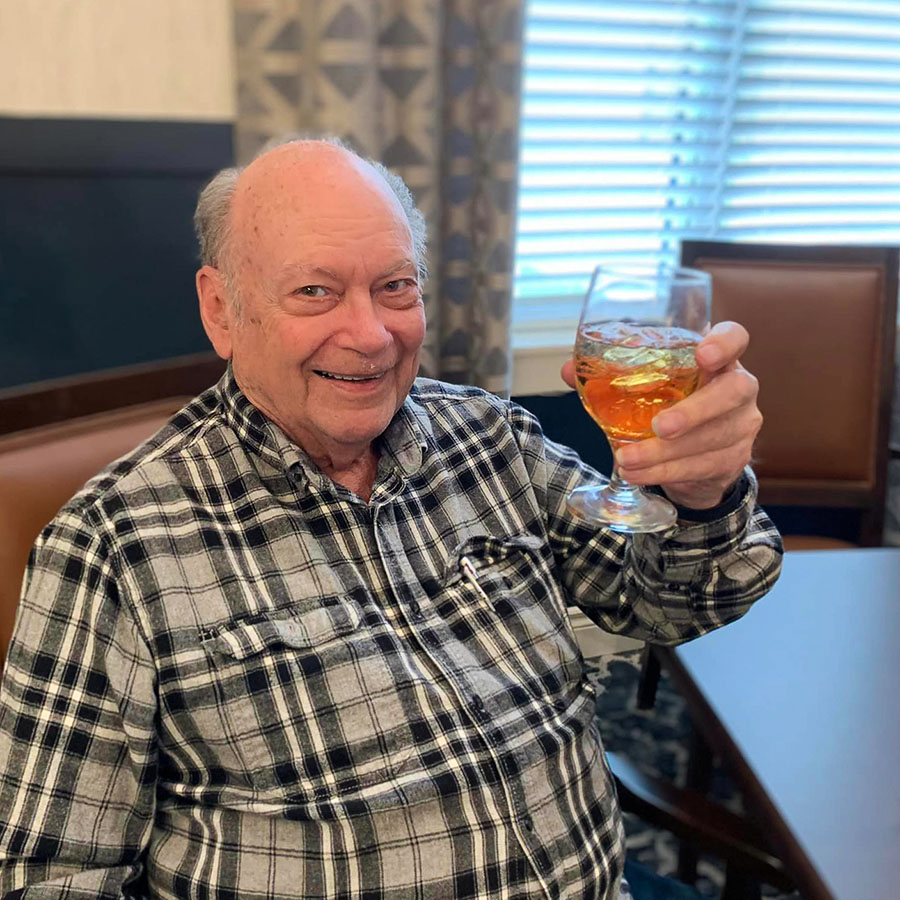 An older man raising a glass of wine in celebration of Chinese New Year.