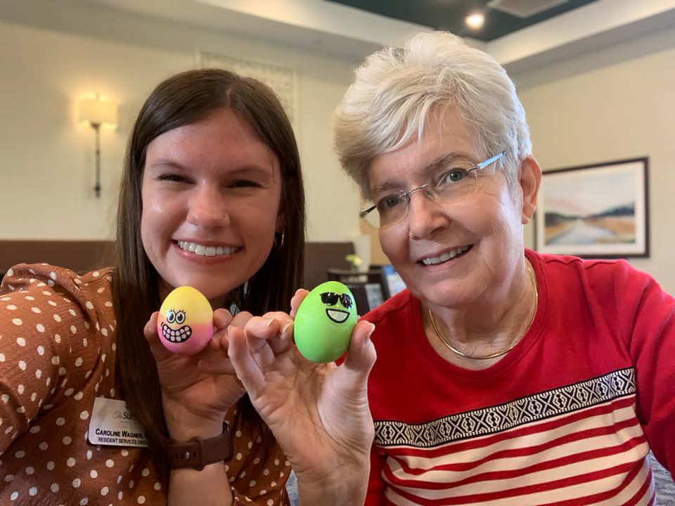 Two joyful women proudly display their beautifully decorated Easter eggs at The The Summit at Chenal Valley Senior Living.