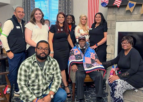 A senior resident who is a member of The Tuskegee Airmen poses with loved ones.