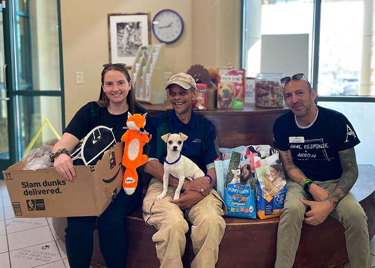 Two members of The Summit team smile with a local business owner, bringing pet supplies.