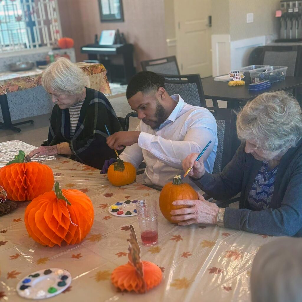 A young man enjoys a pumpkin-themed craft event with residents.
