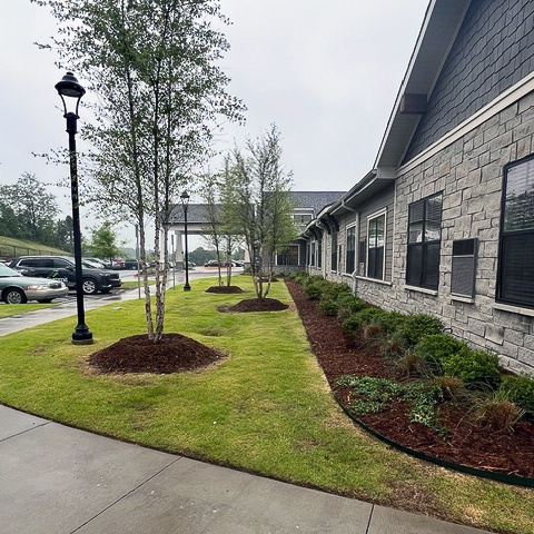 The exterior of The Summit Senior Living at Chenal Valley, showcasing freshly planted foliage.