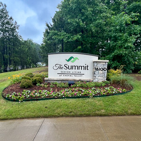 The exterior sign at The Summit, surrounded by landscaped flower beds.