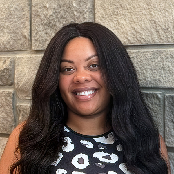 Tyler Ayers, Memory Care Director at The Summit Senior Living, smiling in a professional headshot with long dark hair and a patterned sleeveless top.